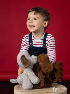 Portrait enfant en studio avec peluches de Noël sur fond rouge