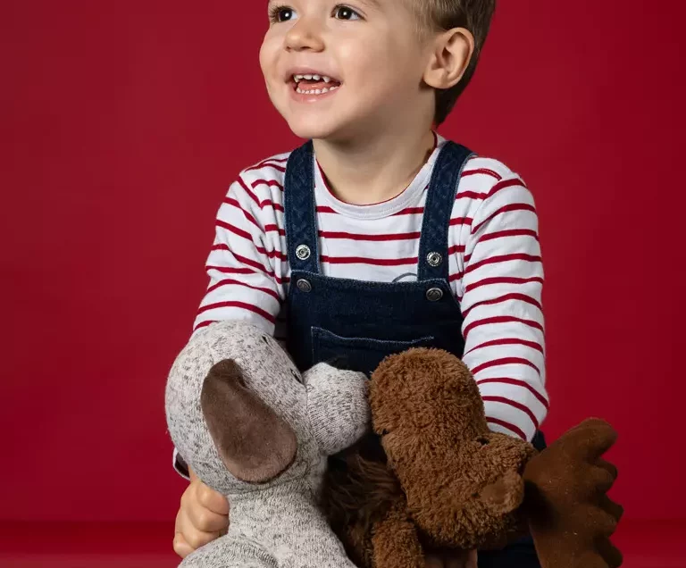 Portrait enfant en studio avec peluches de Noël sur fond rouge